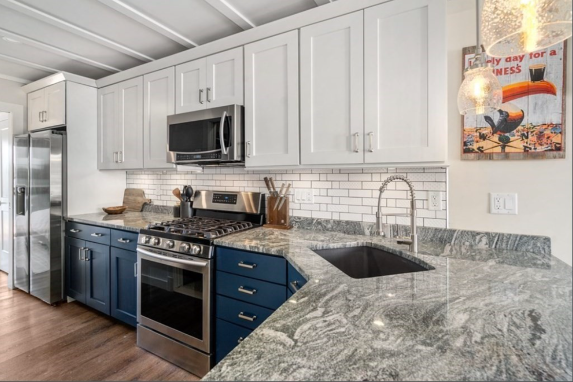 Kitchen with white and blue Shaker-style cabinets, granite countertops, and subway tile backsplash.