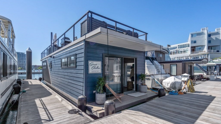 Slate blue houseboat with front porch and upper deck.