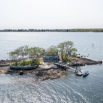 Blue single-family home with white trim, front porch, and 0.27-acre island lot.