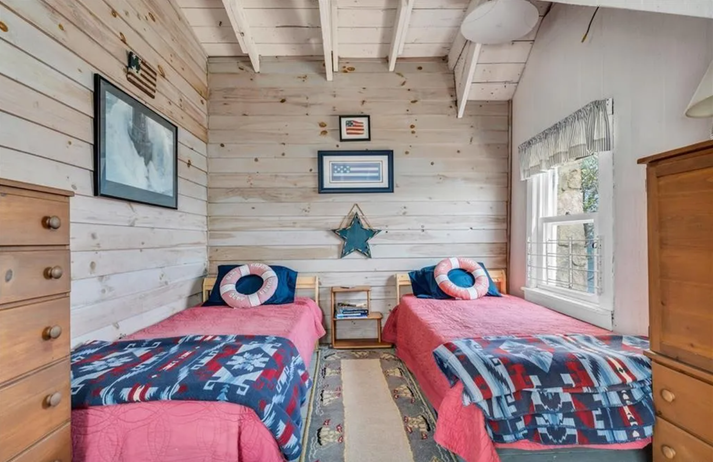 Bedroom with two twin beds, shiplap walls, and single-hung window.