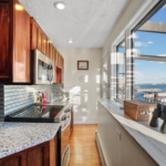 Kitchen with hardwood floors and Shaker-style cabinets. The kitchen is across a hallway from picture windows overlooking Boston Harbor.