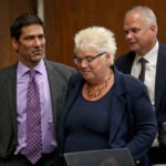 Gary Zerola, left, is wearing a dark gray suit with a light purple shirt and darker purple tie. He has short dark hair. To his right is Rosemary Scapicchio, a woman with short platinum blond hair and a navy shirt and jacket. At the far right is Joseph Krowski, who is wearing a navy suit, white shirt, and dark tie. He has short gray hair.