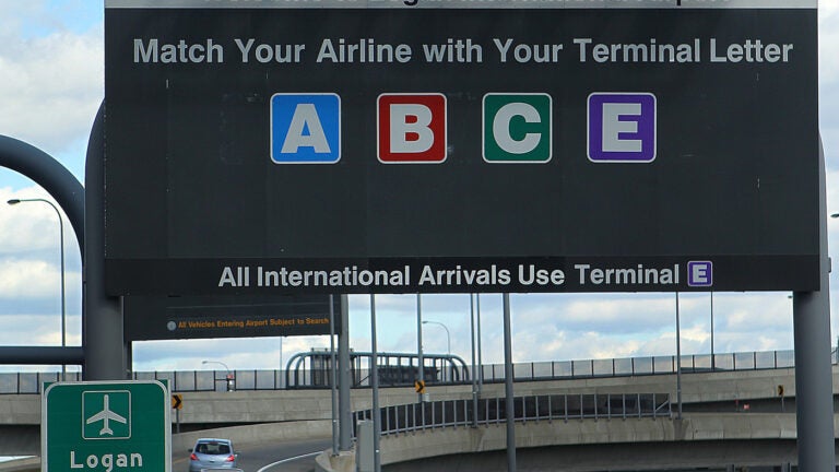 A road sign reads: "Welcome to Logan International Airport. Match your airline with your terminal letter." The letters A, B, C, and E are listed; D is missing.