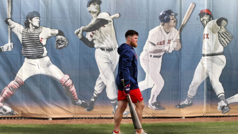 Red Sox infielder Christian Arroyo walks past the mural that pictures Red Sox legends, including (left to right) Carlton Fisk, Ted Williams, Wade Boggs and Luis Tiant.