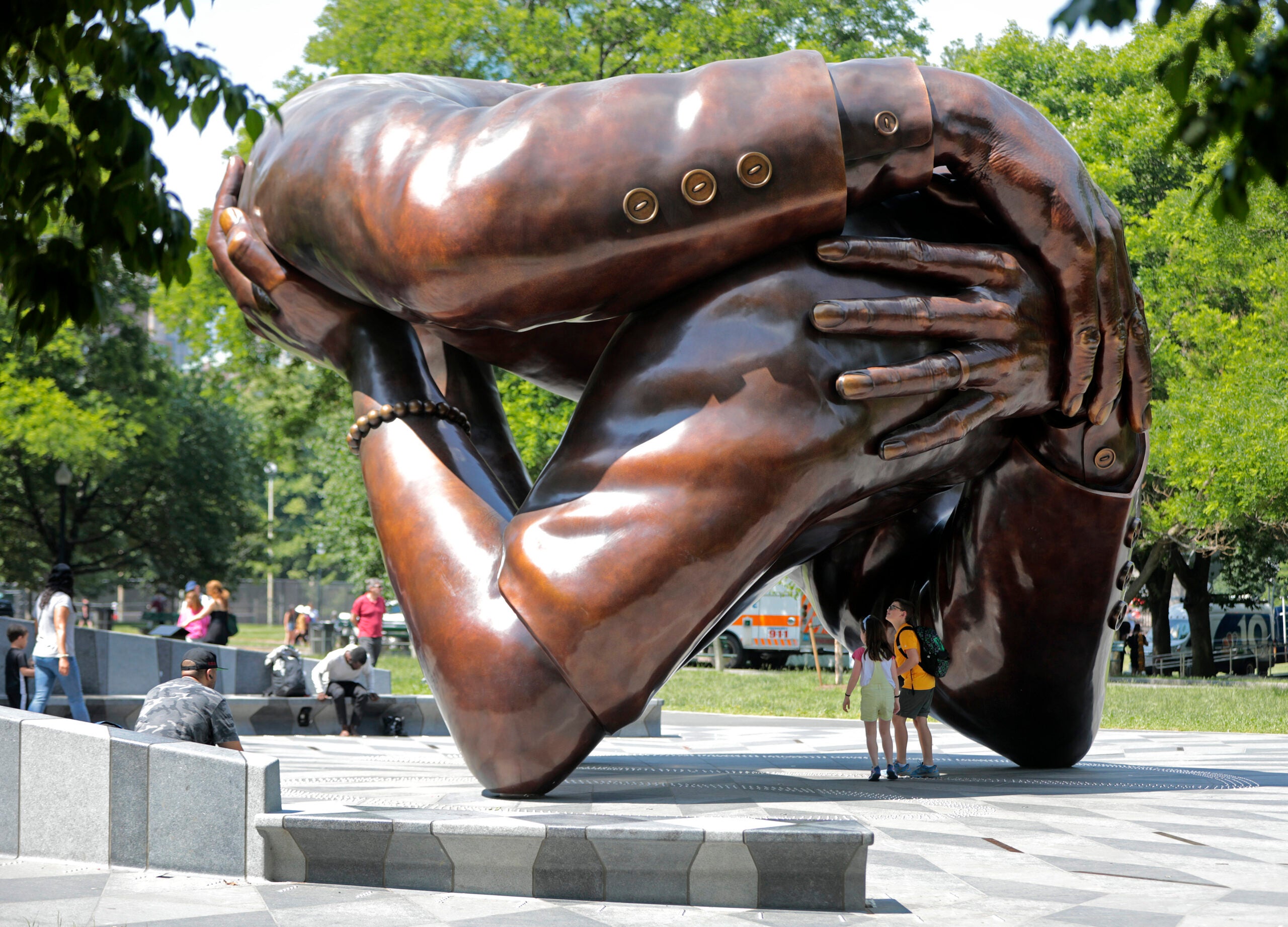 People mingle around the Embrace sculpture