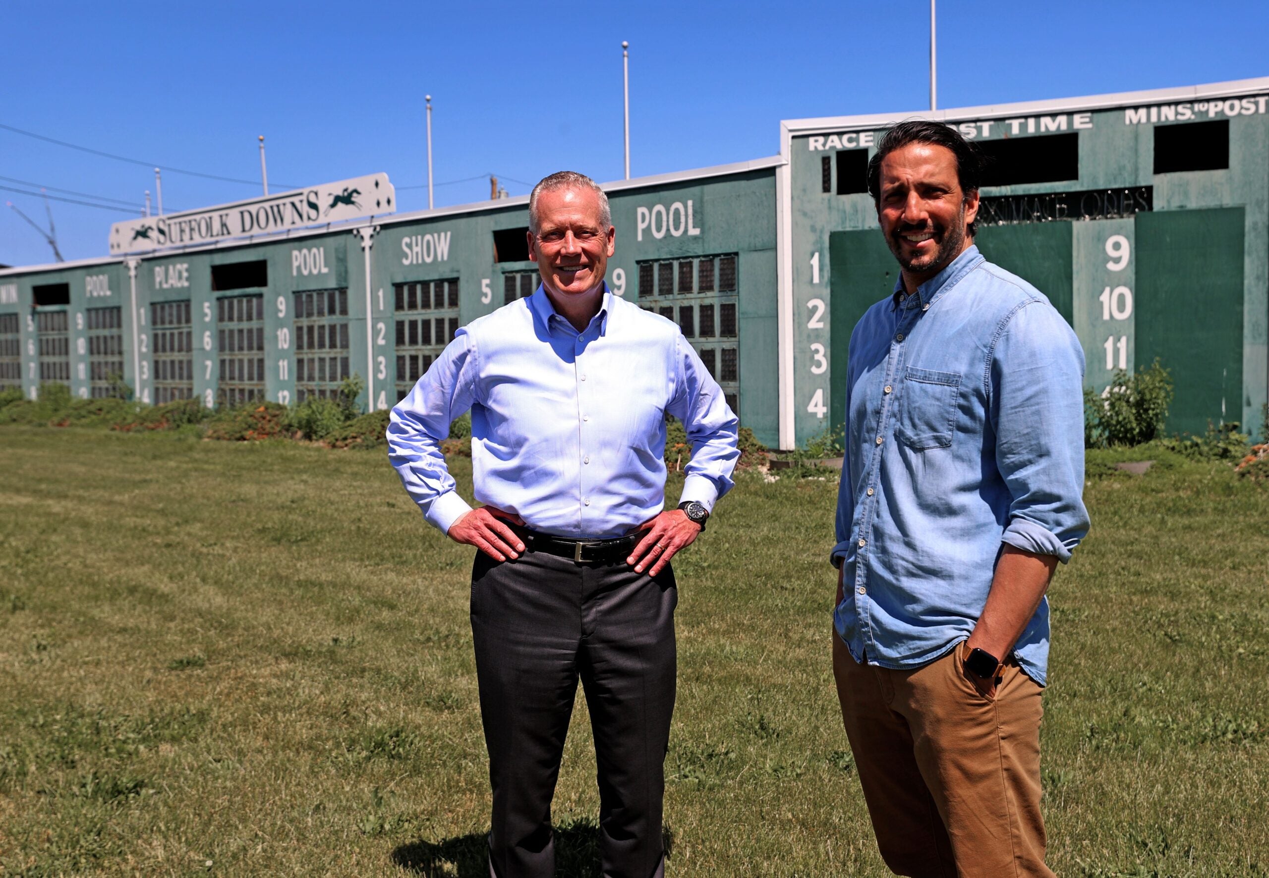 Tom O’Brien, managing partner and chief executive officer of HYM and Josh Bhatti, senior vice president of The Bowery Presents, stand in front of the old Suffolk Downs scoreboard.