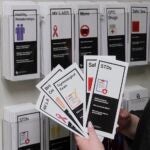 A person is standing out of frame, holding a handful of pamphlets about sexual education, with topics ranging from birth control to STDs.