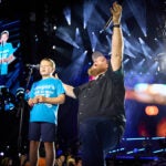 A young boy and a man sing a song at a concert