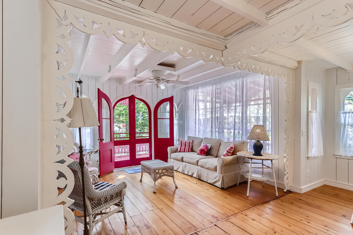 A white room with exposed beams and a bright pink arched door.
