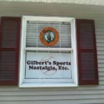 The Gilbert's Sports Nostalgia sign in the window of the store.