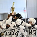 08bruins - Bruins prospects Mason Langenbrunner (93) Mason Lohrei (84) and Jake Schmaltz (83) and teammates gather around a trophy given to the winner of a three-on-three tournament during the last day of Bruins development camp at Warrior Arena.