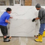 Two men move quartz slabs.