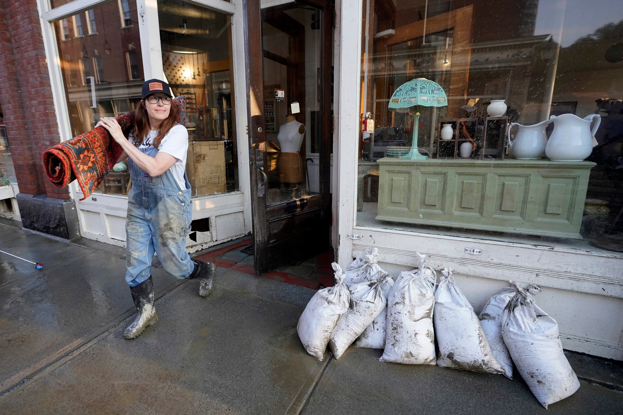 Juliana Jennings, of Montpelier, Vt., removes a wet Persian rug from the flood-damaged antique, art, and furnishing store J. Langdon.
