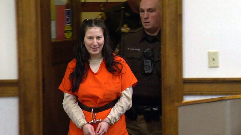 Taylor Schabusiness stands in court room with her hands cuffed together.