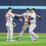 Three outfielders begin to hug.