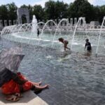 Visitors and tourists to the World War II Memorial seek relief from the hot weather in the memorial's fountain on July 3, 2023 in Washington, DC.