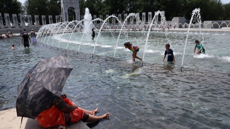 Visitors and tourists to the World War II Memorial seek relief from the hot weather in the memorial's fountain on July 3, 2023 in Washington, DC.