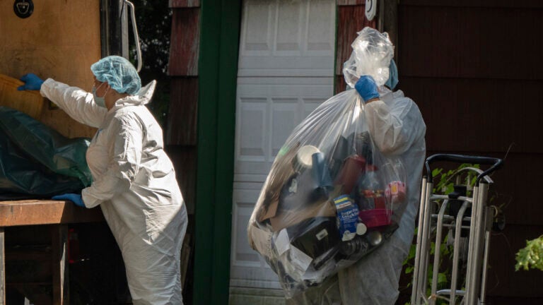 A crime laboratory officer moves a plastic bag of items as law enforcement searches the home of Rex Heuermann, Saturday, July 15, 2023, in Massapequa Park, New York.