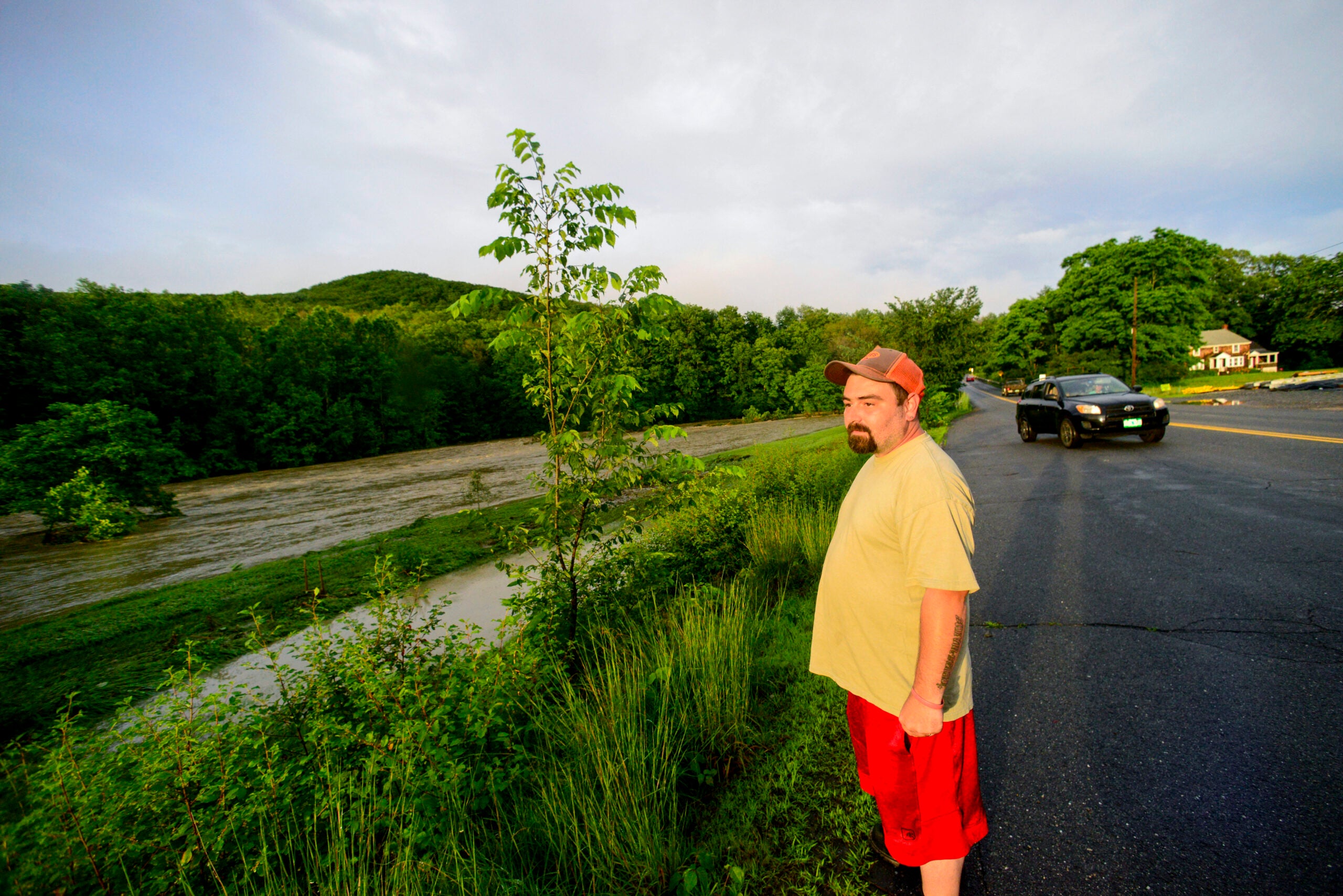 Leonard Derby, of Athens, Vt., watches the floodwaters from the Saxtons River pass through a field on Route 121 in Rockingham, Vt.