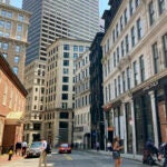Pedestrians cross a street, Tuesday, July 11, 2023, in downtown Boston.