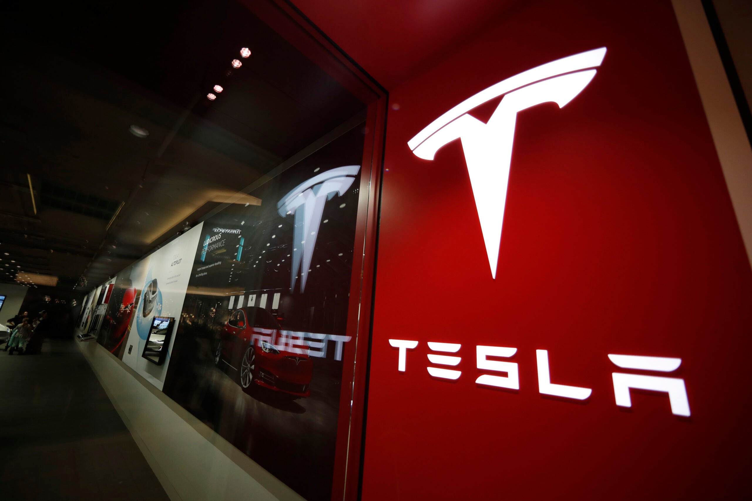 FILE - A sign bearing the Tesla company logo is displayed outside a Tesla store in Cherry Creek Mall in Denver, Feb. 9, 2019.