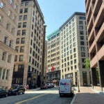 A Fedex truck drives down a strees in downtown Boston, amid towering office buildings.