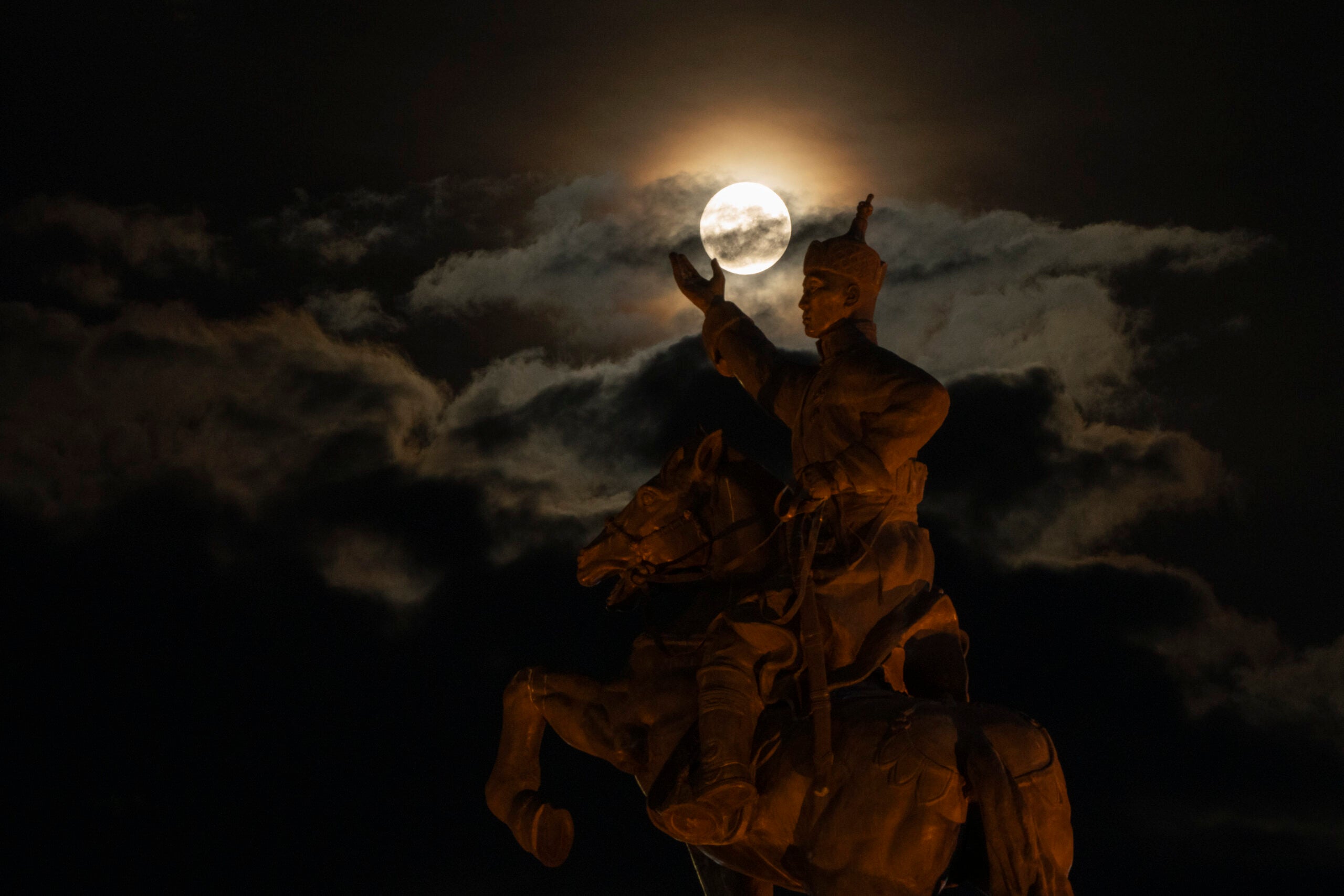 The supermoon rises near the equestrian statue of Damdin Sukhbaatar on Sukhbaatar Square in Ulaanbaatar, Mongolia.
