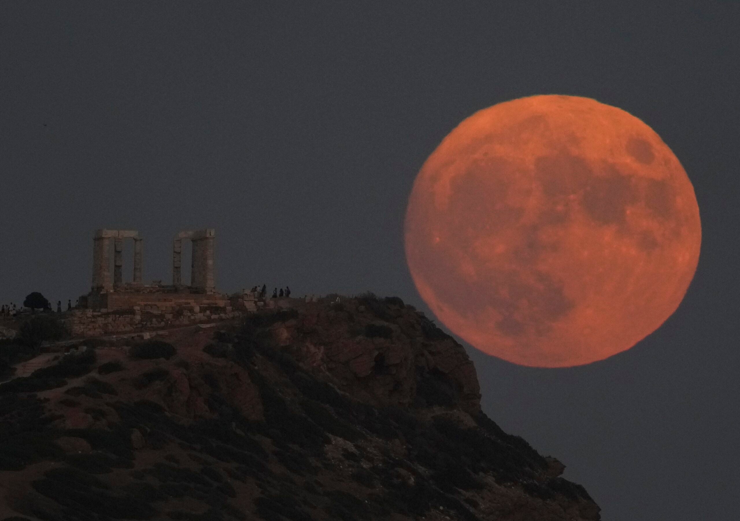 The supermoon rises behind the ancient temple of Poseidon at Cape Sounion.