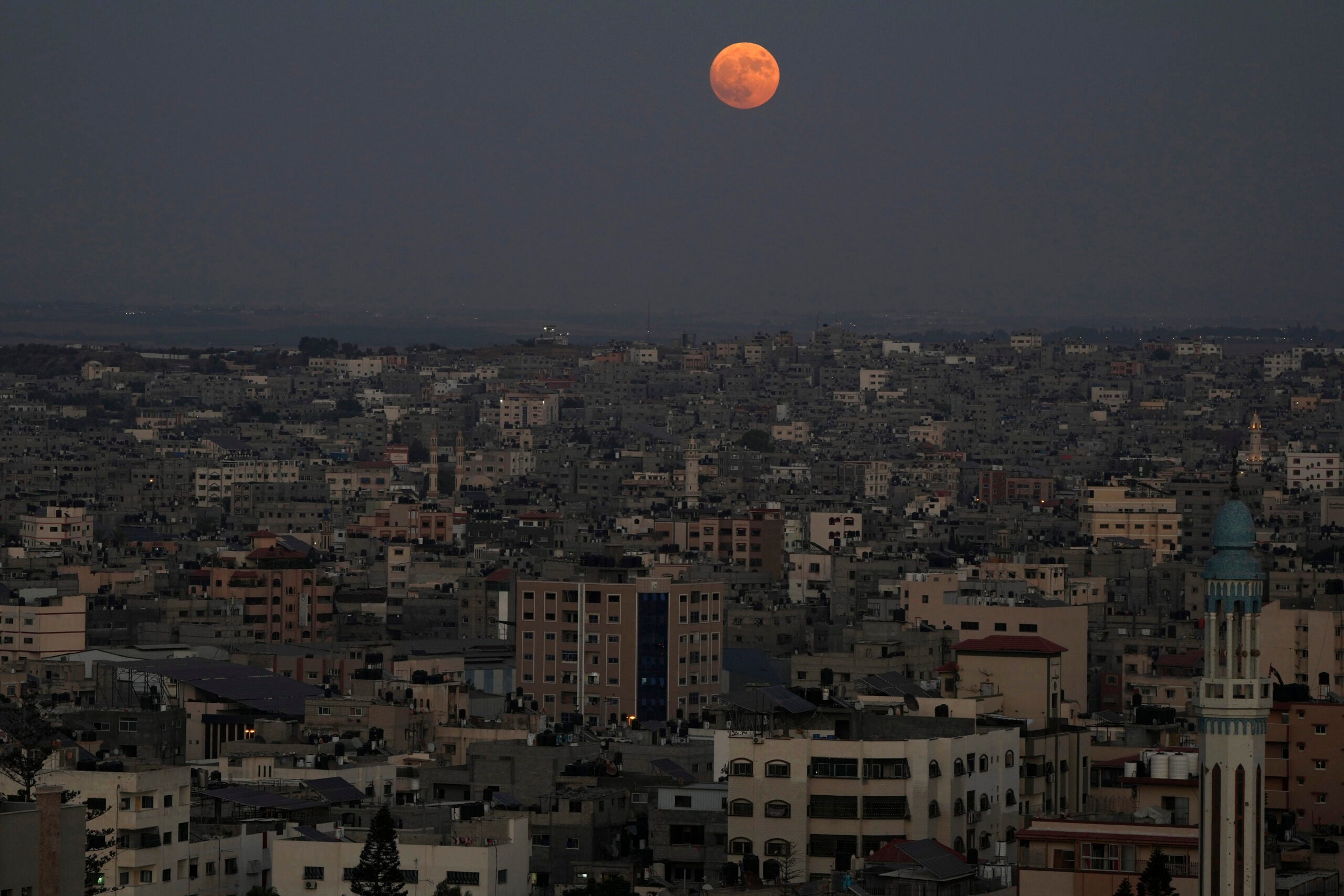 The supermoon rises in the sky over the houses of Gaza City.