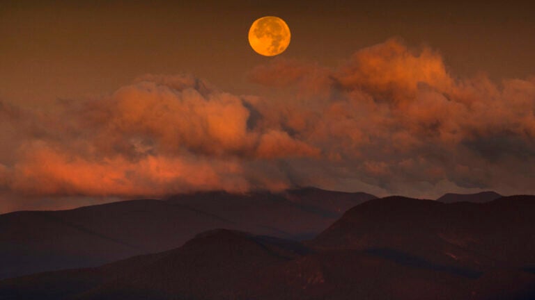 The blue supermoon sets over the White Mountain National Forest at sunrise.
