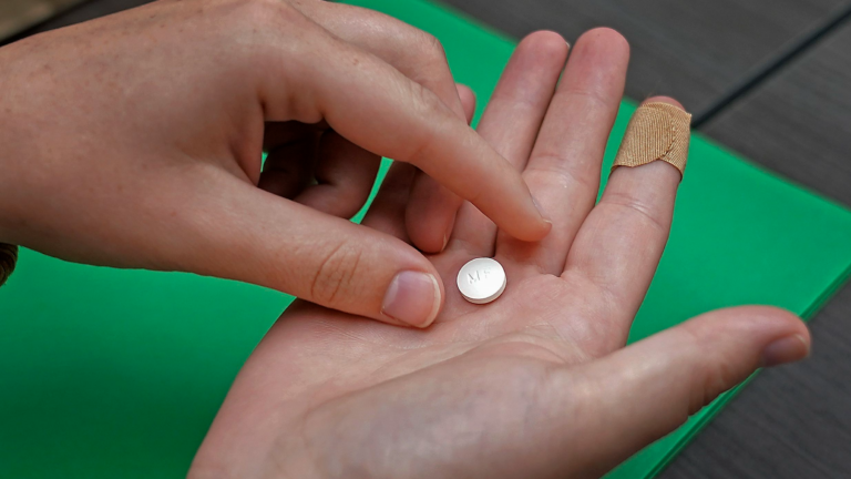 A mifepristone pill sits in someone's open palm.