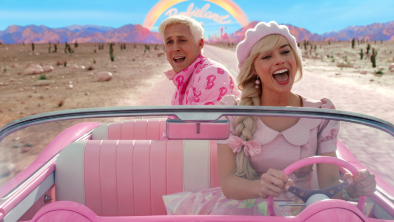Ryan Gosling and Margot Robbie as Ken and Barbie in a scene from "Barbie." They're driving through a desert in a pink convertible, singing a song.
