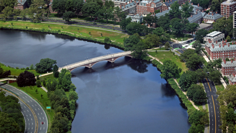 An aerial view of a bending river with a bridge connecting the two banks.