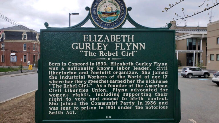 A dark green historical marker with white lettering dedicated to Elizabeth Gurley Flynn in Concord, New Hampshire.