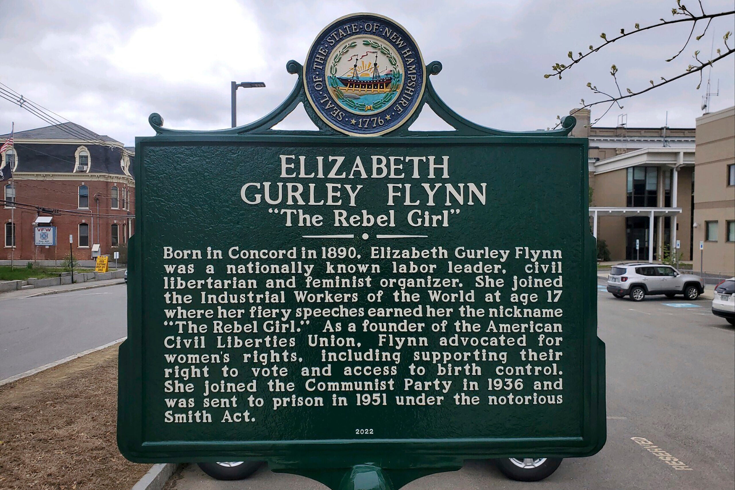 A dark green historical marker with white lettering dedicated to Elizabeth Gurley Flynn in Concord, New Hampshire.