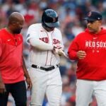 A Boston Red Sox trainer and manager Alex Cora check on Rafael Devers after he was hit by a pitch during the eighth inning of a baseball game, Saturday, Aug. 26, 2023, in Boston.