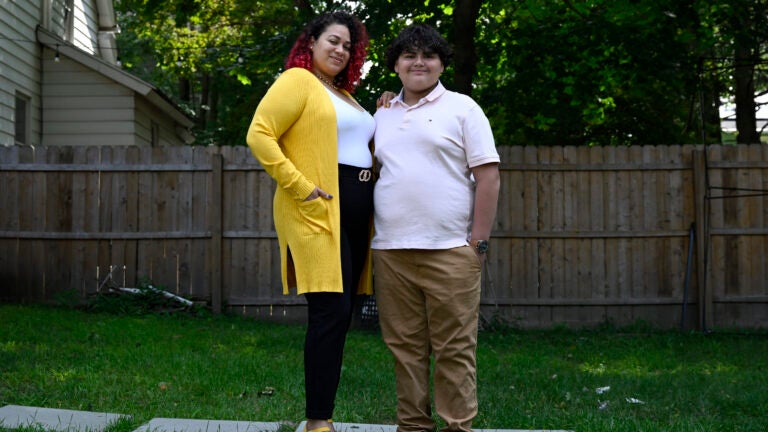 Rousmery Negrón stands with her son outside at home in Springfield, Mass.