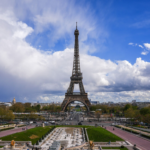 The Eiffel Tower is pictured from across a grassy park.