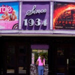 A patron buys a movie ticket underneath a marquee featuring the films "Barbie" and "Oppenheimer."