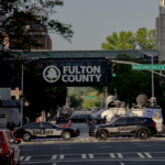 A bridge emblazoned with the words "Fulton County" stands over a busy intersection