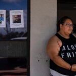 Guadalupe Gonzalez, a Lahaina, Hawaii, resident who survived a deadly wildfire, stands next to missing person flyers.