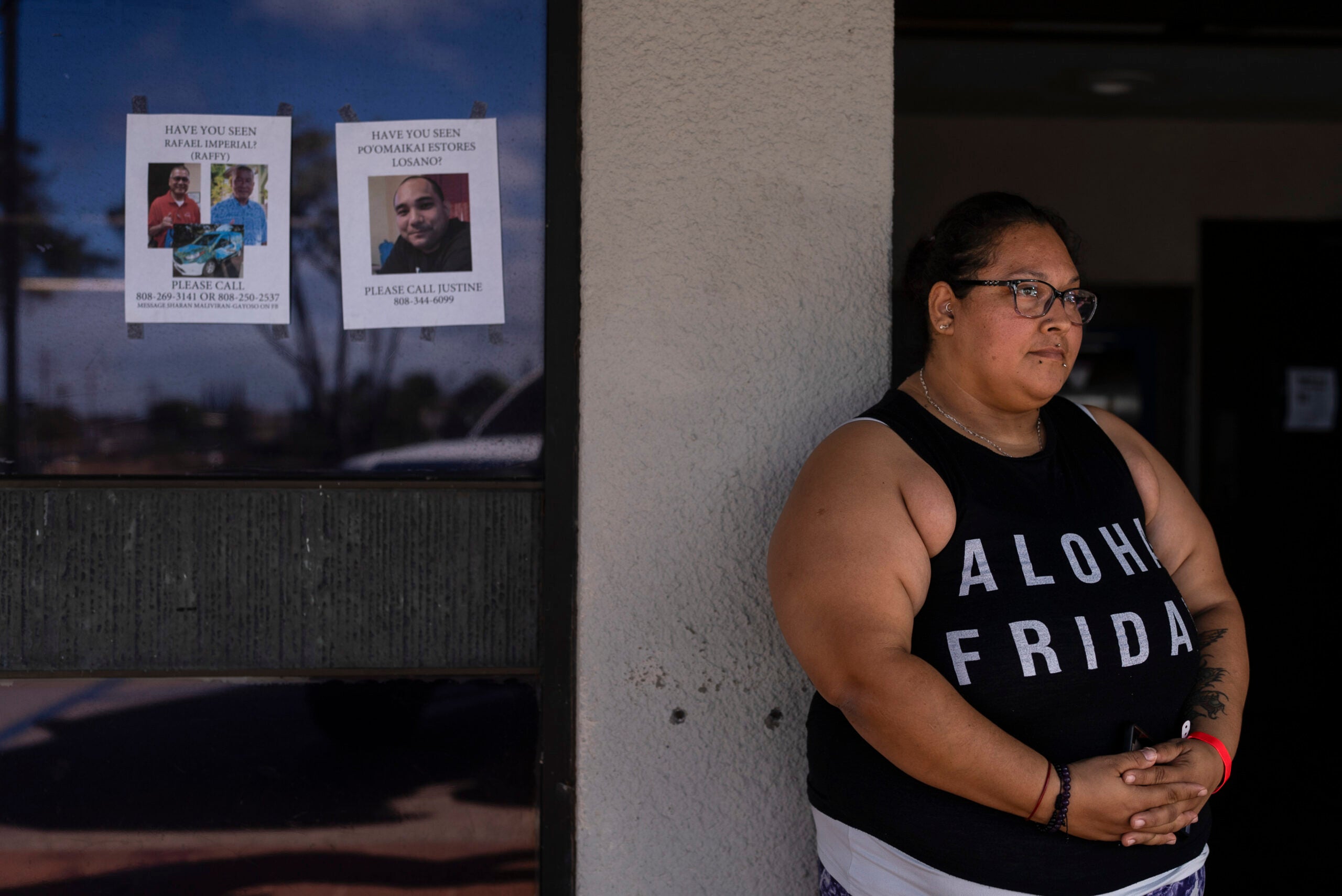Guadalupe Gonzalez, a Lahaina, Hawaii, resident who survived a deadly wildfire, stands next to missing person flyers.