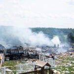 Two firefighters stand on the debris around the smoldering wreckage of the three houses that exploded near Rustic Ridge Drive and Brookside Drive in Plum, Pa., on Saturday, Aug. 12, 2023.