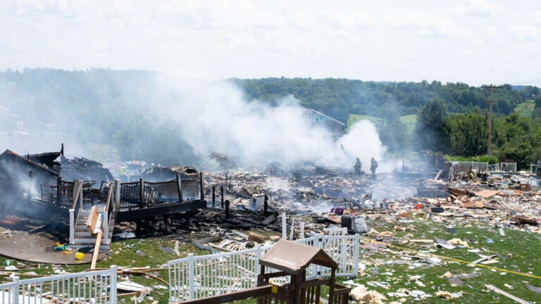Two firefighters stand on the debris around the smoldering wreckage of the three houses that exploded near Rustic Ridge Drive and Brookside Drive in Plum, Pa., on Saturday, Aug. 12, 2023.