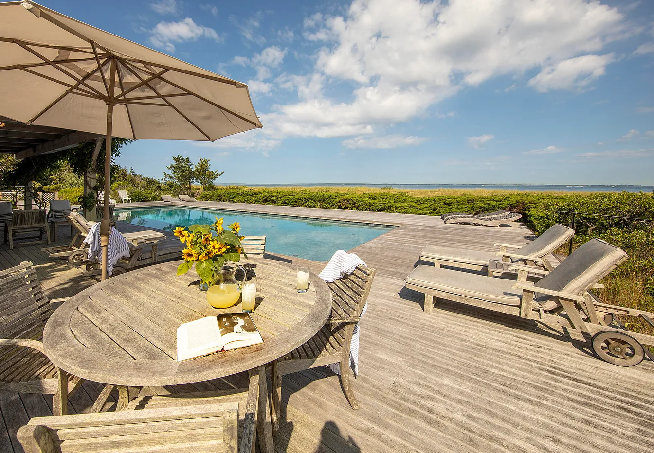 Pool area with wooden deck and furniture overlooking Vineyard sound.