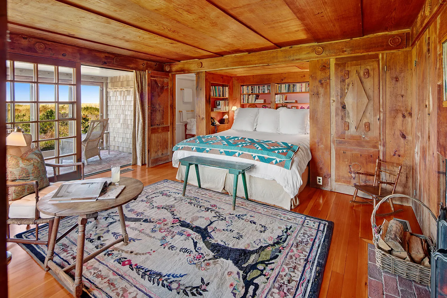 Bedroom with wood walls, and sliding glass door overlooking waterfront in Martha's Vineyard.