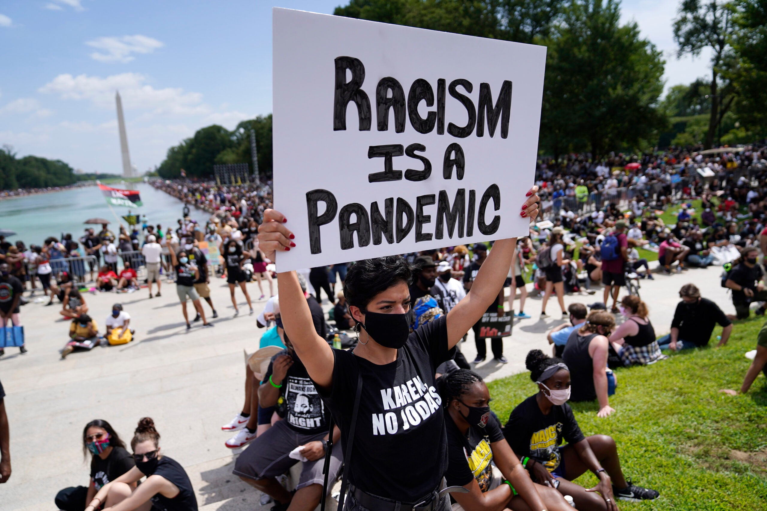 Priscilla Duerrero holds a sign reading "Racism Is A Pandemic" during the March on Washington.