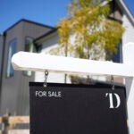 a for-sale sign in front of a home to illustrate mortgage rates