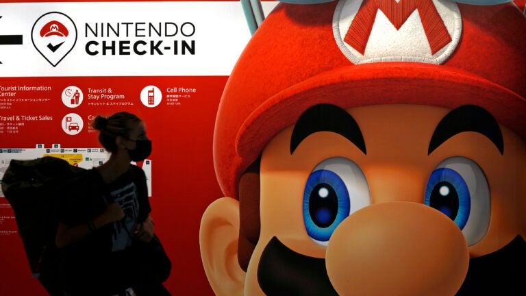 FILE - A person passes an ad featuring the Nintendo character Mario at Narita airport in Narita near Tokyo.