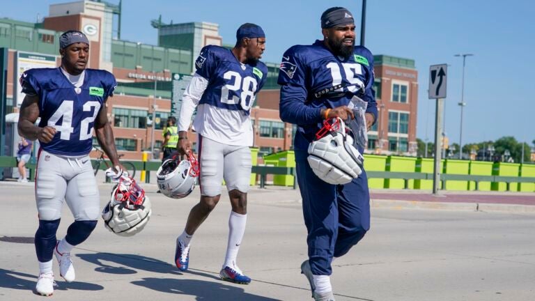 New England Patriots' Ezekiel Elliott along with J.J. Taylor (42) and Ameer Speed (28) walk to practice for NFL football training camp Wednesday, Aug. 16, 2023, in Green Bay, Wis.